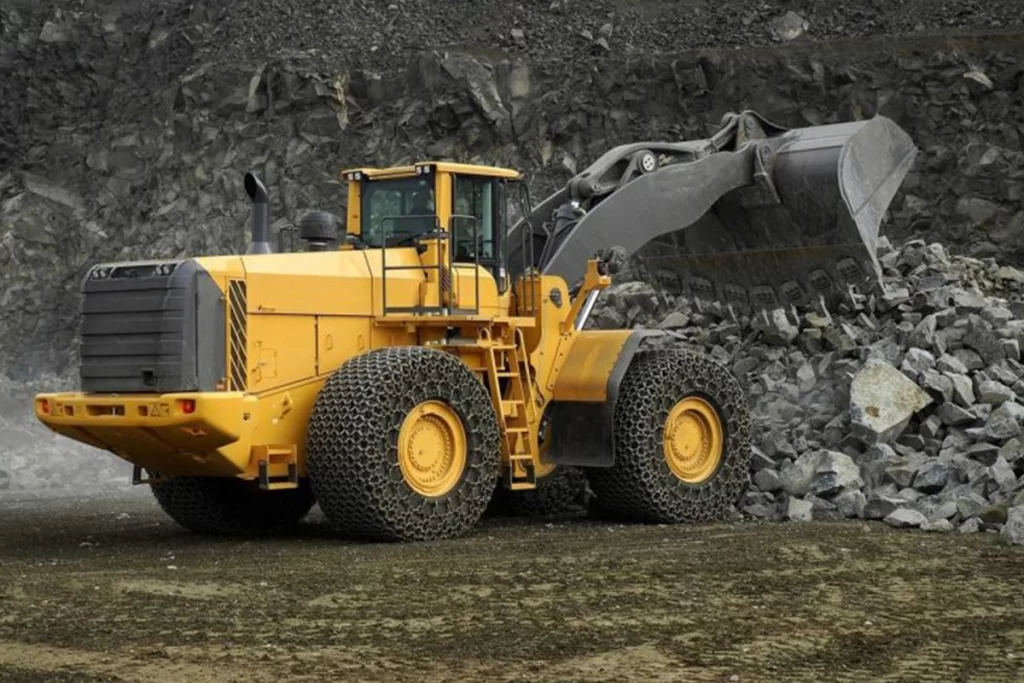 A yellow bulldozer pushes rock and cement into a pile.