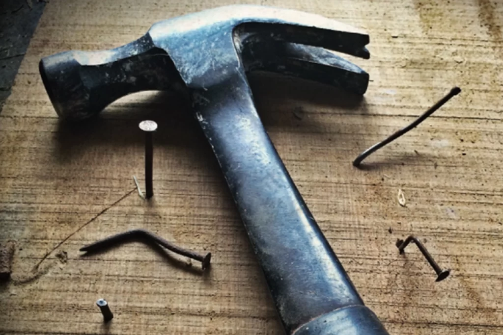 A hammer surrounded by bent nails.