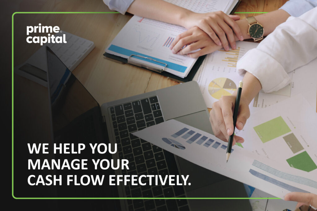 Two people sit at a desk looking at pages of charts. Below one of the papers, it reads, "We Help You Manage Your Cash Flow Effectively."