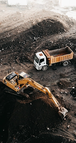 A yellow excavator digs up dirt to drop in the back of a truck.