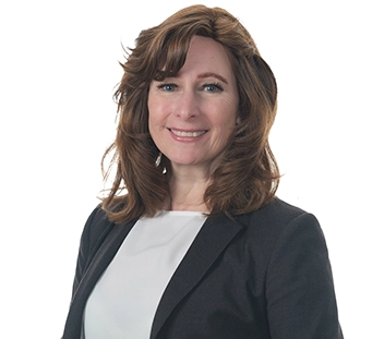 Prime Capital Founder and CEO Angela Armstrong wears a black blazer with white blouse and smiles at the camera.